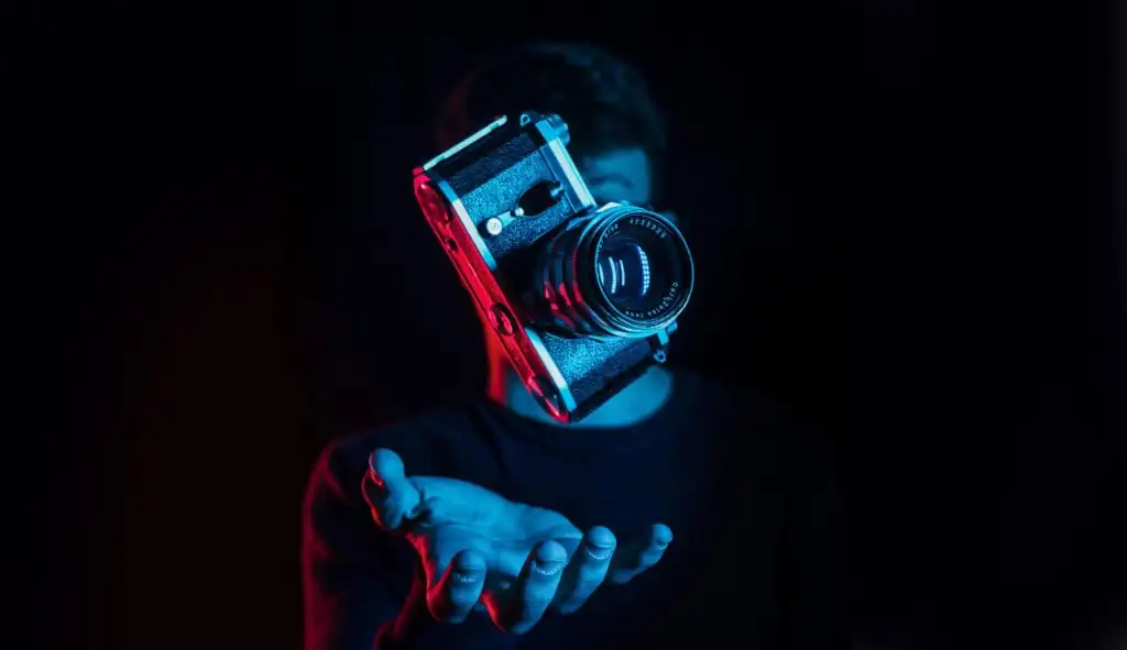 Photographer catching a falling slr camera on a black background