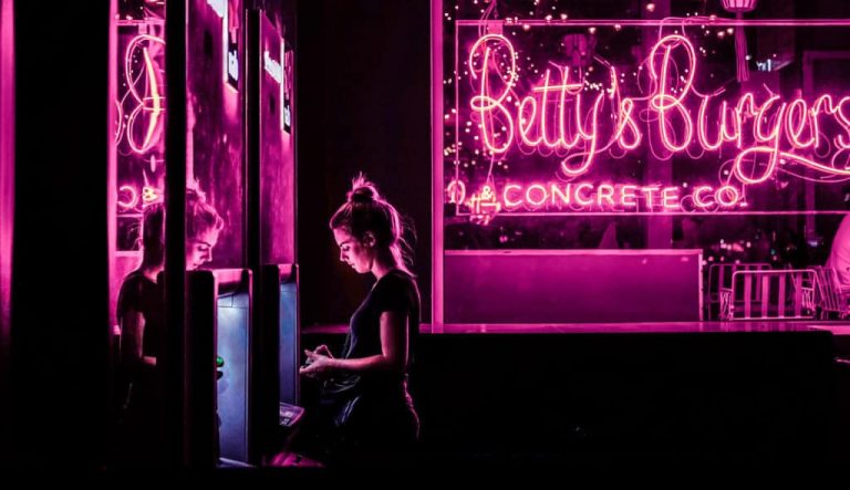 Image of a restaurant owner with her logo in the front window in neon